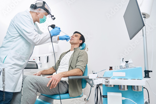 Doctor examining man with medical instrument at the hospital