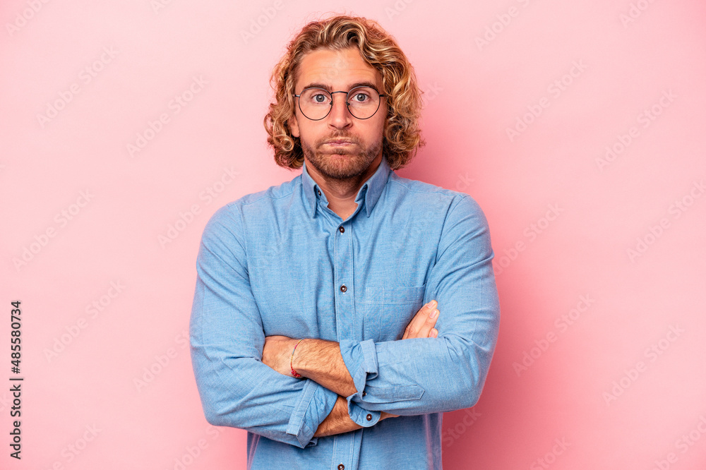 Young caucasian man isolated on pink background blows cheeks, has tired expression. Facial expression concept. Young caucasian man isolated on pink background blows cheeks, has tired expression. Facial expression concept.