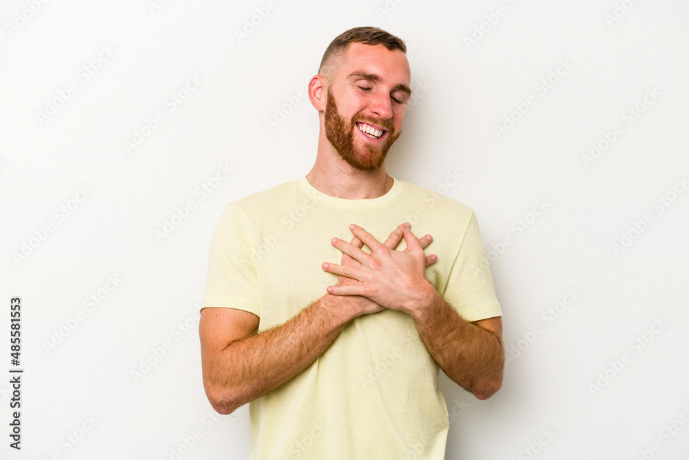 Young caucasian man isolated on white background laughing keeping hands on heart, concept of happiness. Young caucasian man isolated on white background laughing keeping hands on heart, concept of happiness.