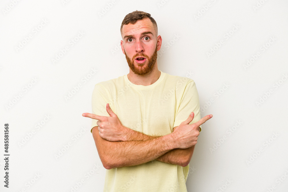 Young caucasian man isolated on white background points sideways, is trying to choose between two options. Young caucasian man isolated on white background points sideways, is trying to choose between two options.