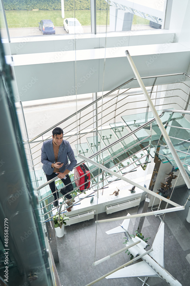 Male with travel documents and phone leaning on stair railing Male with travel documents and phone leaning on stair railing