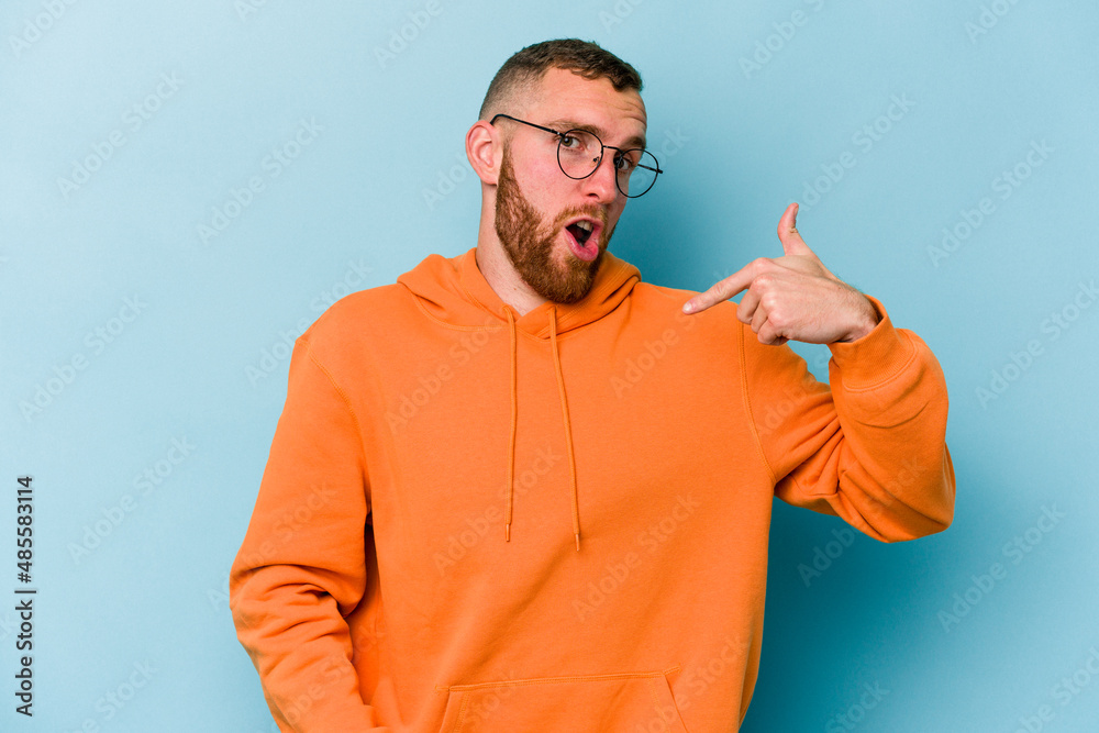 Young caucasian man isolated on blue background person pointing by hand to a shirt copy space, proud and confident Young caucasian man isolated on blue background person pointing by hand to a shirt copy space, proud and confident