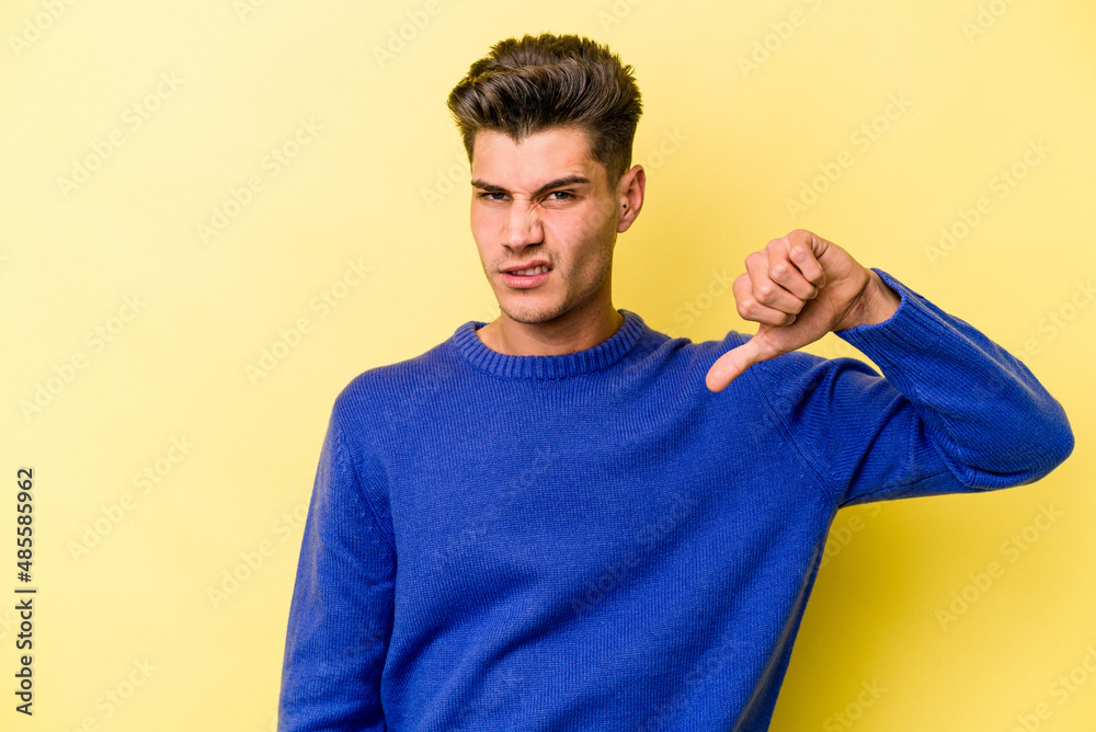 Young caucasian man isolated on yellow background showing thumb down, disappointment concept. Young caucasian man isolated on yellow background showing thumb down, disappointment concept.