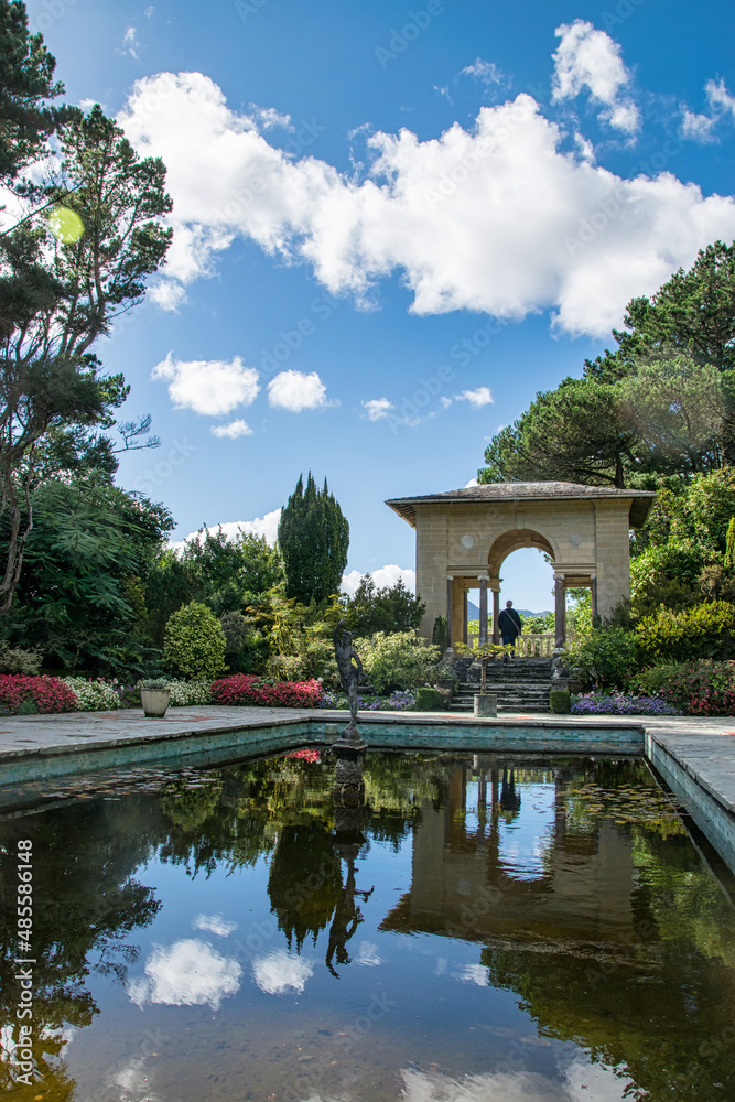 Ein wunderschön angelegter Garten mit einem Torbogen und einem Teich, der die Szenerie spiegelt Ein wunderschön angelegter Garten mit einem Torbogen und einem Teich, der die Szenerie spiegelt