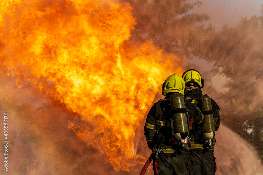 firefighters wearing fire fighter suit for safety and using twirl water extinguisher for fighting the fire flame in emergency situation.. - Safety Firefighter and industrial concept.