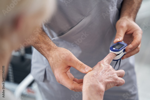 Doctor applying pulse oximeter to patient finger