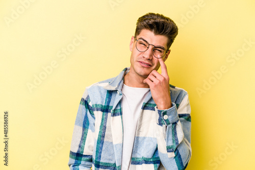Young caucasian man isolated on yellow background crying, unhappy with something, agony and confusion concept. © Asier