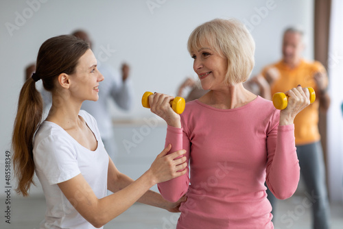 Fitness instructor assisting multiracial group of elderly people