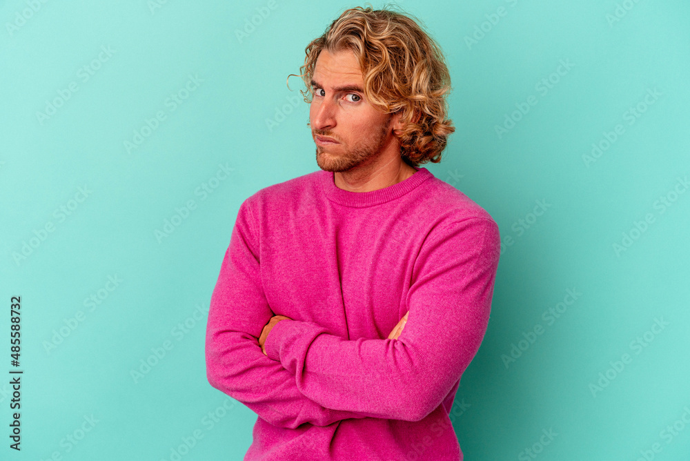 Young caucasian man isolated on blue background suspicious, uncertain, examining you. Young caucasian man isolated on blue background suspicious, uncertain, examining you.