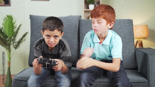 sad teener kid asking for game pad to his brother at home - concpet of multiethnic siblings, video game addiction and entertainment.