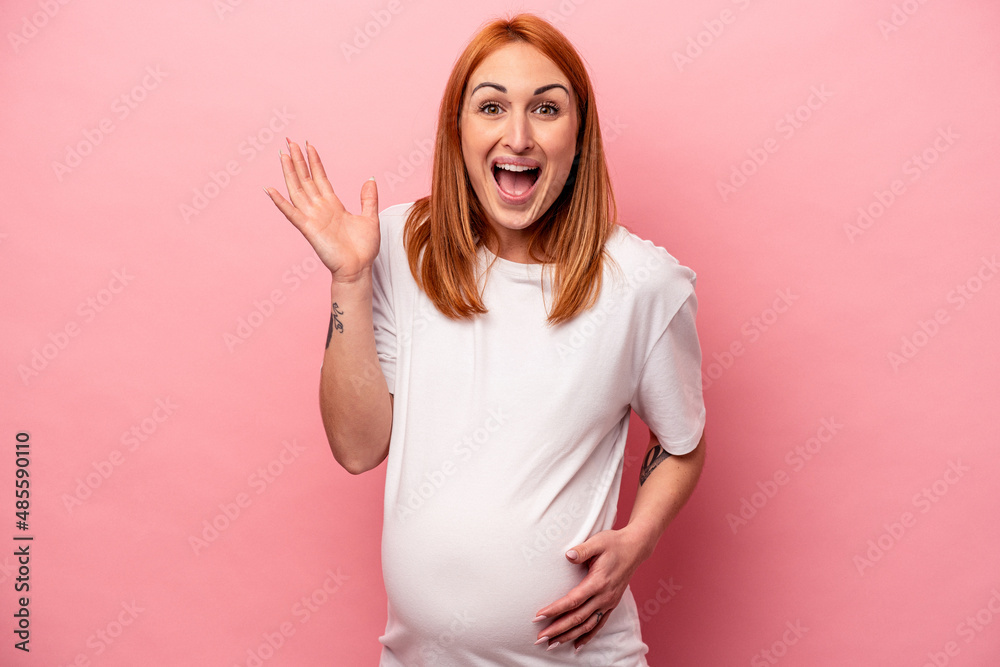 Young caucasian pregnant woman isolated on pink background receiving a pleasant surprise, excited and raising hands. Young caucasian pregnant woman isolated on pink background receiving a pleasant surprise, excited and raising hands.
