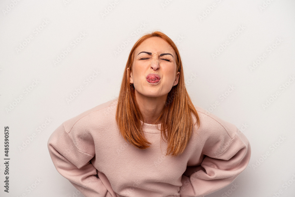 Young caucasian woman isolated on white background funny and friendly sticking out tongue.