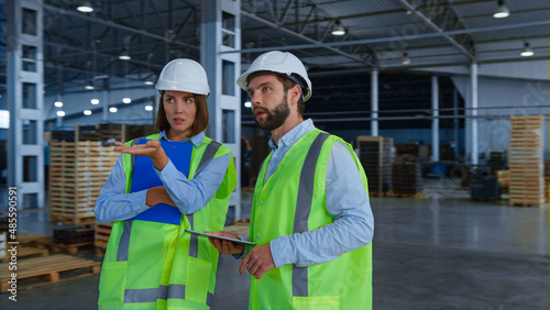 Warehouse specialists checking factory production holding tablet papers talking