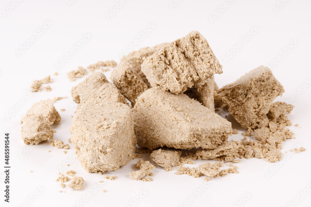 a large pile of halva with crumbs on a white background