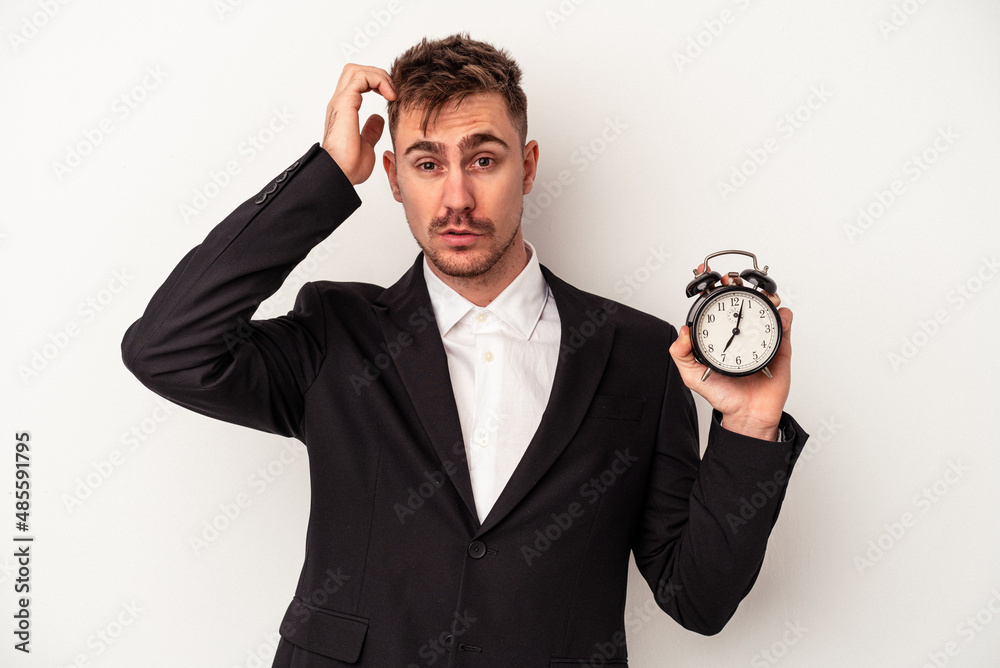 Young caucasian business man holding alarm clock isolated on white background being shocked, she has remembered important meeting. Young caucasian business man holding alarm clock isolated on white background being shocked, she has remembered important meeting.