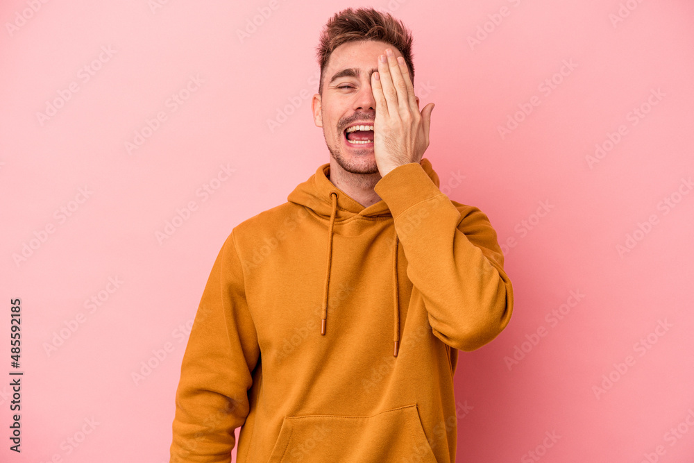 Young caucasian man isolated on pink background having fun covering half of face with palm. Young caucasian man isolated on pink background having fun covering half of face with palm.