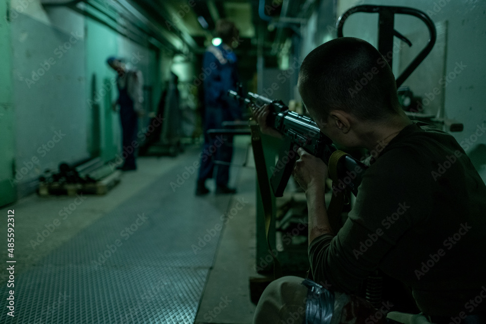Back view shot of female soldier shooting zombies in dark hallway, copy space Back view shot of female soldier shooting zombies in dark hallway, copy space