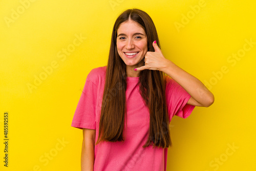 Young caucasian woman isolated on yellow background showing a mobile phone call gesture with fingers. © Asier