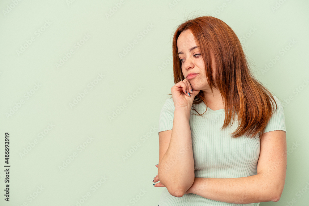 Young caucasian woman isolated on green background looking sideways with doubtful and skeptical expression. Young caucasian woman isolated on green background looking sideways with doubtful and skeptical expression.