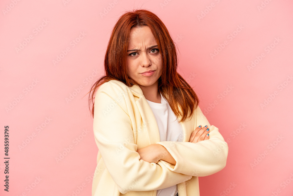 Young caucasian woman isolated on pink background frowning face in displeasure, keeps arms folded. Young caucasian woman isolated on pink background frowning face in displeasure, keeps arms folded.