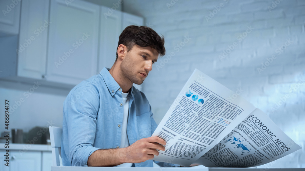 man in blue shirt reading morning newspaper while sitting in kitchen man in blue shirt reading morning newspaper while sitting in kitchen