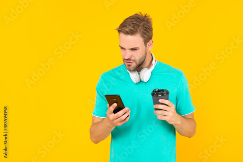 guy with coffe check sms on yellow background, communication