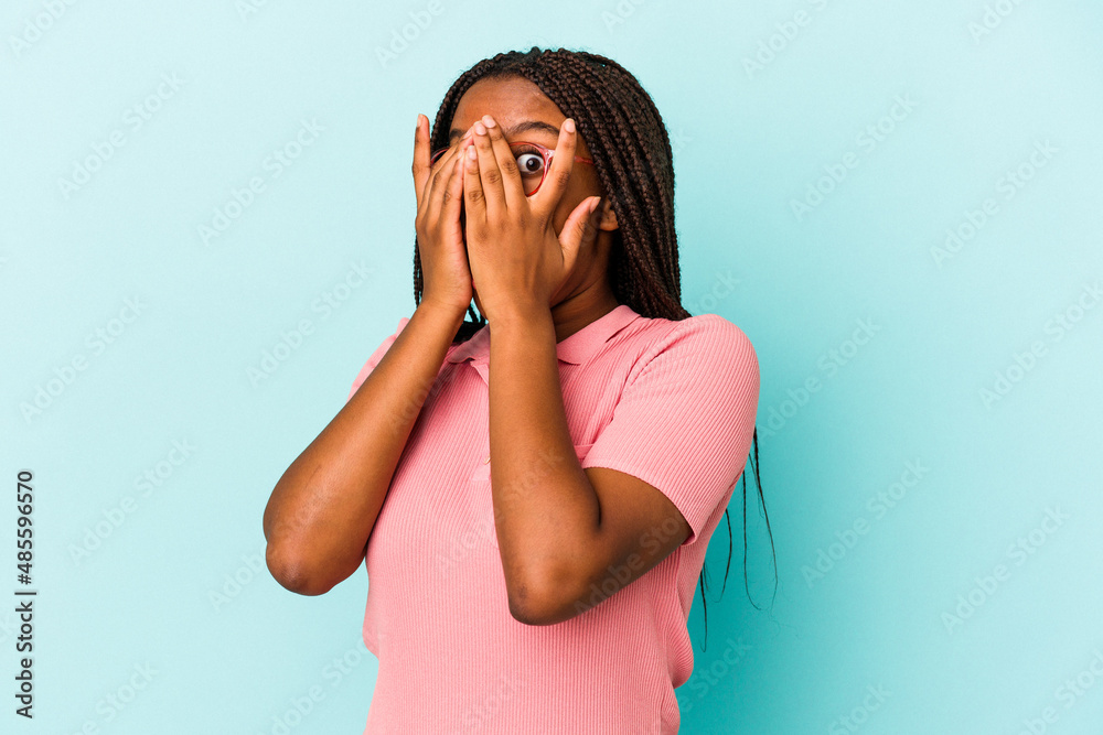 Young african american woman isolated on blue background blink through fingers frightened and nervous. Young african american woman isolated on blue background blink through fingers frightened and nervous.