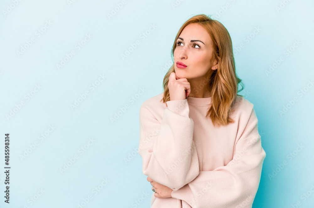 Young caucasian woman isolated on blue background looking sideways with doubtful and skeptical expression. Young caucasian woman isolated on blue background looking sideways with doubtful and skeptical expression.