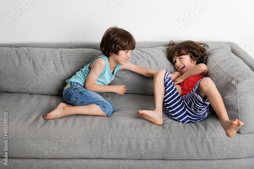 Twin brothers tickling each other on couch photo