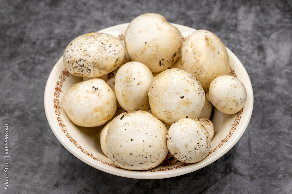 Mushrooms in a ceramic plate on a dark floor. Cultivated mushroom or portabello mushroom Mushrooms in a ceramic plate on a dark floor. Cultivated mushroom or portabello mushroom