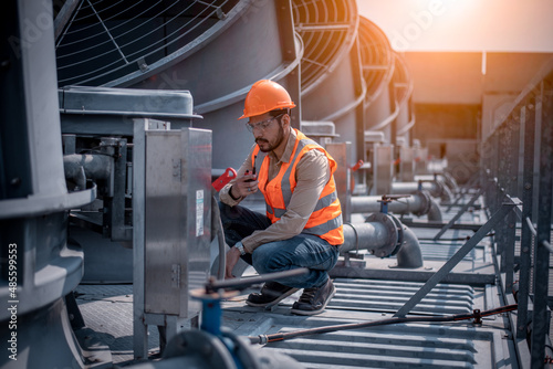 engineer under checking the industry cooling tower air conditioner is water cooling tower air chiller HVAC of large industrial building to control air system. photo