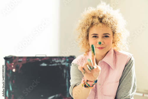 Portrait of an young female painter artist - showing the dirty finger to the camera. High quality photo
