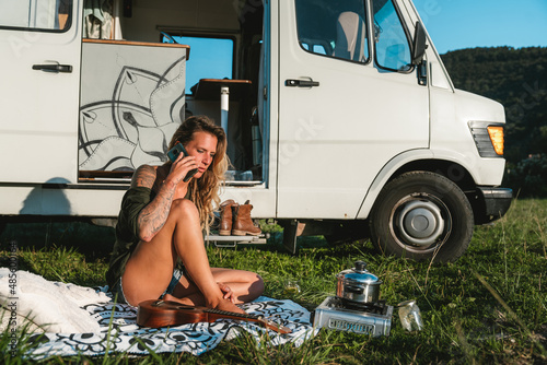 Woman talking on smartphone near camping van photo