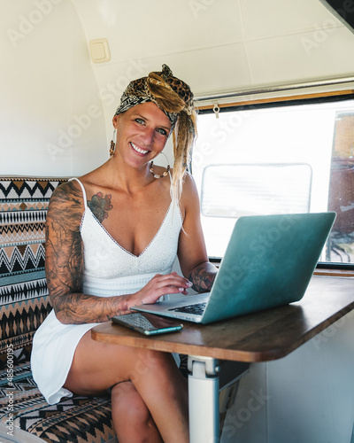 Happy woman browsing laptop in camper van photo