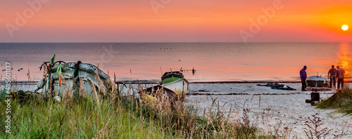 Coastal landscape with fishing boats and silhouettes of fishermen at dawn, Ba...