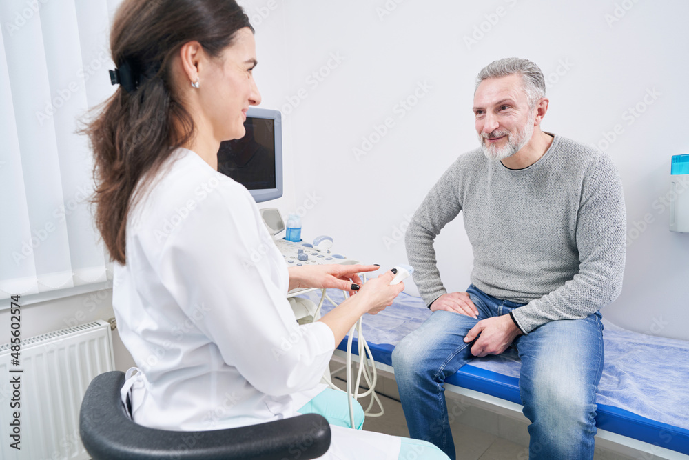 Obraz premium Friendly young sonographer communicating with patient before ultrasonography