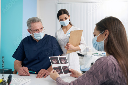 Focused woman looking at fetal ultrasound pictures after sonography photo