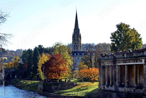 Church with a steeple on the bank of the River Avon  surrounded by autumn foliage  in Bath  England