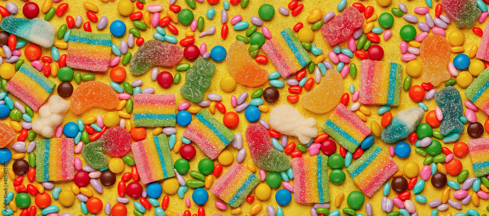 Colorful assortment of candies   on yellow background. Top view, banner