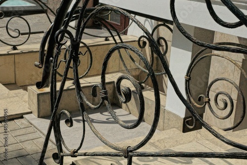 handrails of black iron bars in a wrought pattern at brown steps on a city street