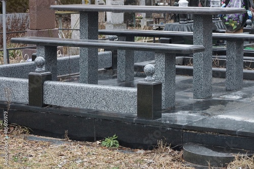 gray bench and table of stone and marble with black stone barrier at the grave in the cemetery © butus