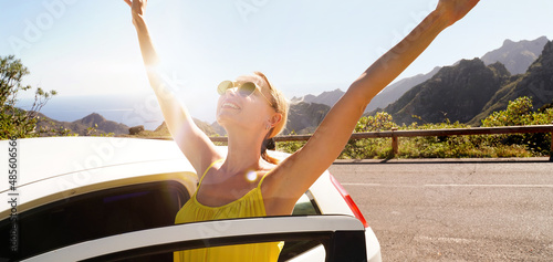 Happy smiling woman enjoying a car road trip along the mountainous landscape during sunrise, off-road trip.