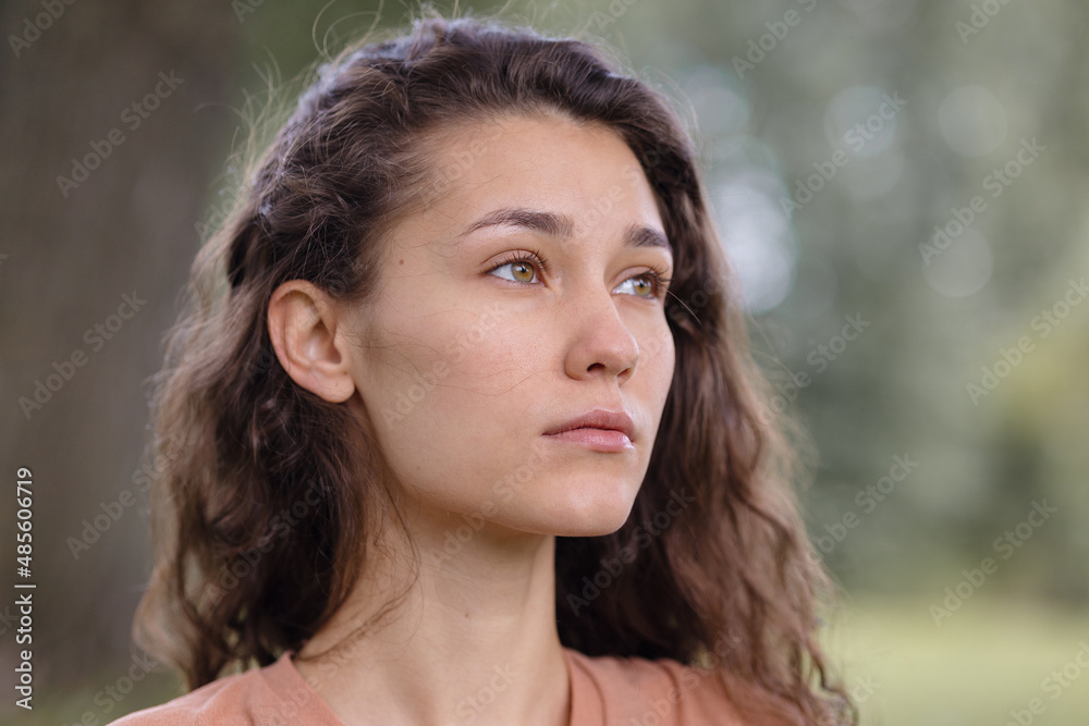 Fototapeta premium a woman with curly hair meditates in the park. yoga and meditation for mental and physical health. a beautiful young woman calmly looks thoughtfully and engages in breathing and spiritual practices