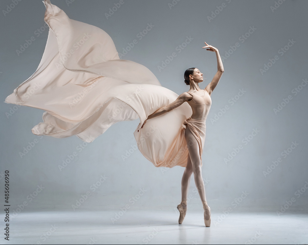 Fototapeta premium Beautiful ballerina dancing in the body color ballet leotard with body color cloth. She danced on ballet pointe shoes.