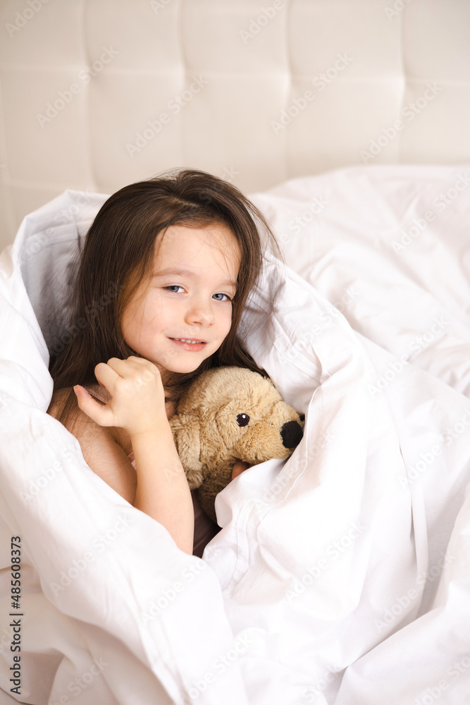 A pretty little girl woke up in her bed and stretches and yawns in the bedroom in the morning. A new day. Lifestyle. A pretty little girl woke up in her bed and stretches and yawns in the bedroom in the morning. A new day. Lifestyle.