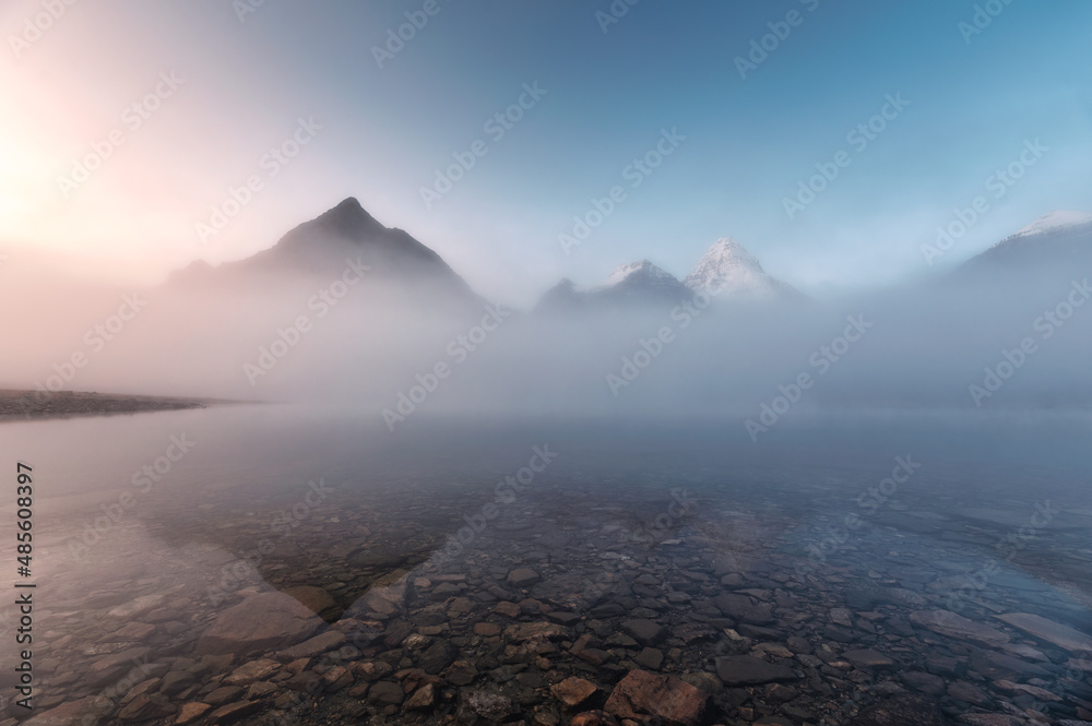 Scenery of sunrise over Rocky mountains in foggy reflection on Lake Magog at Assiniboine provincial park