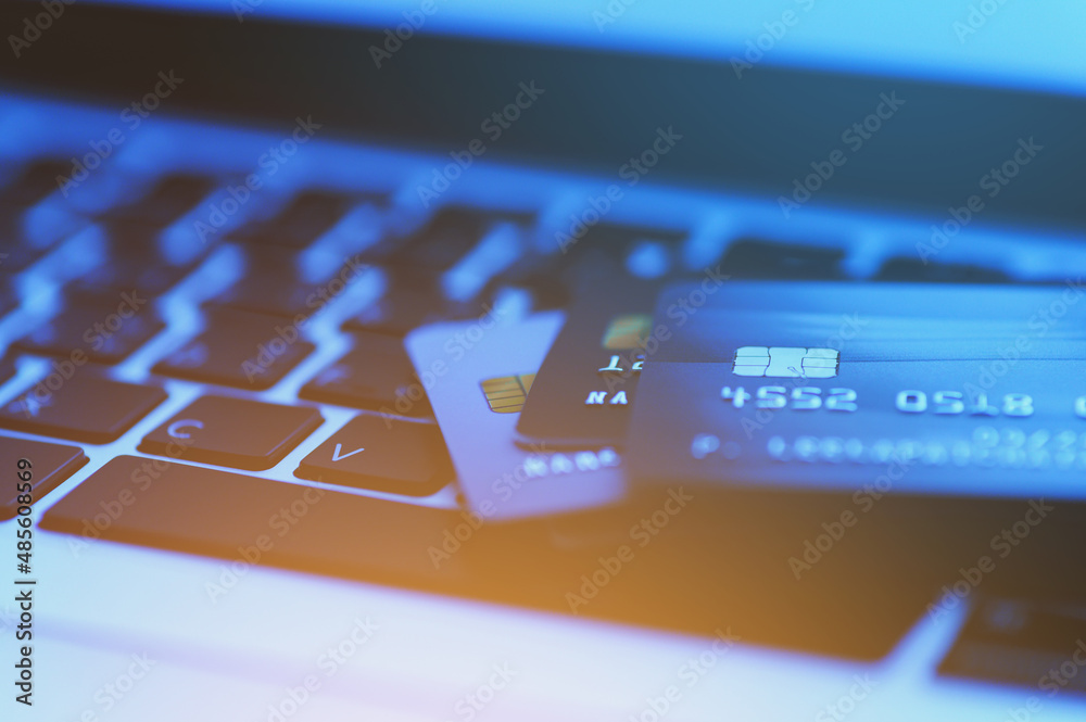Close-up shot of credit card on Laptop computer payment for purchases from online stores and online shopping. Concept of internet purchase. Blue color tone and selective focus for background. Close-up shot of credit card on Laptop computer payment for purchases from online stores and online shopping. Concept of internet purchase. Blue color tone and selective focus for background.