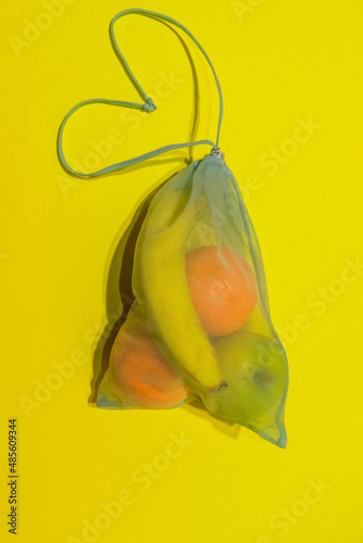  Fruit lies in a reusable bag for shopping on a yellow background. Vertical photo. High quality photo