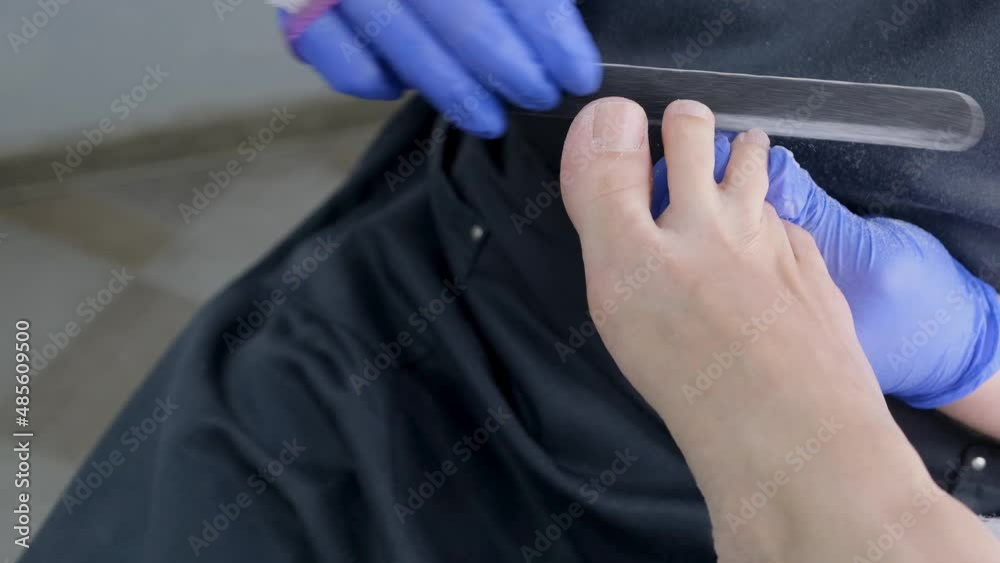 master makes a pedicure to a client in a beauty salon, using a foot nail file, peeling the skin of the feet. Close up, selective focus. master makes a pedicure to a client in a beauty salon, using a foot nail file, peeling the skin of the feet. Close up, selective focus.