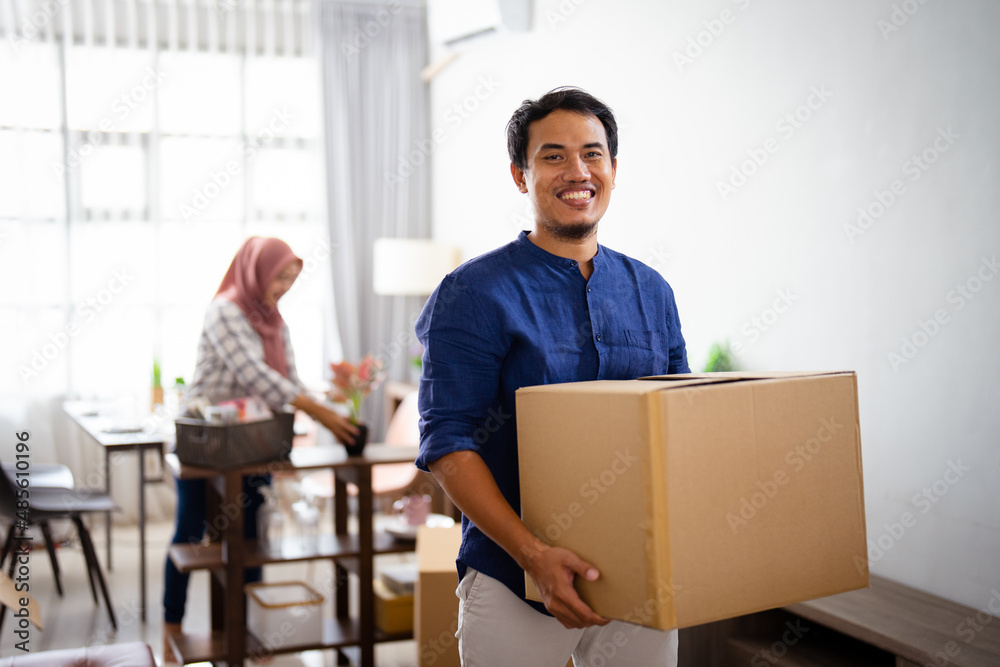 young man looking at camera while carrying his cardboard young man looking at camera while carrying his cardboard